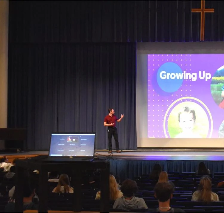 Evan presenting on stage with a Growing Up slide behind him